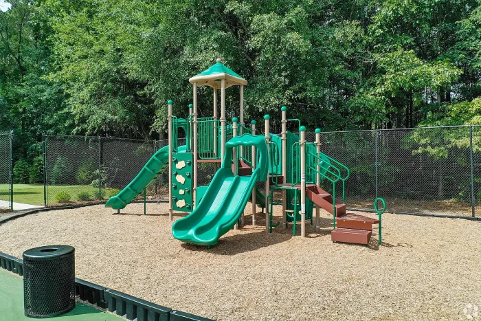 Vibrant outdoor playground with slides and climbing structures surrounded by lush greenery, perfect for family-friendly living.