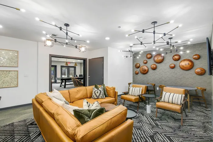 Modern and inviting resident lounge area with sleek lighting fixtures, stylish leather sofas, contemporary wall art, and a cozy ambiance.