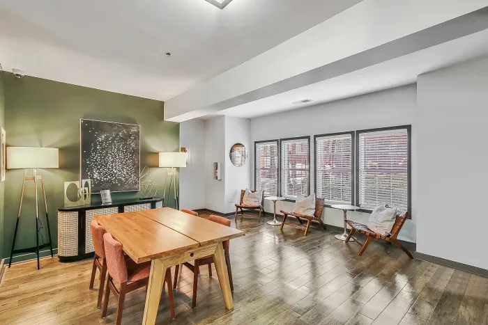 Bright, modern resident clubroom with elegant wood flooring, stylish dining area, and chic decor accents.