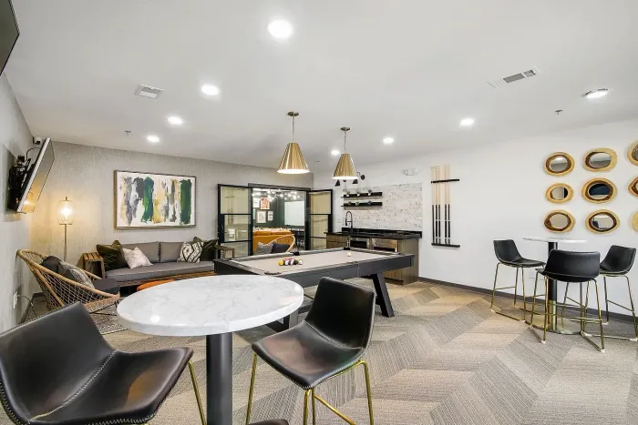 Chic resident lounge with a pool table, modern seating area, and stylish kitchen in a vibrant, well-lit space.