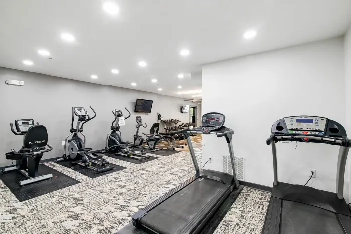Modern fitness center with state-of-the-art treadmills, ellipticals, and stationary bikes, featuring a sleek design and ample lighting.