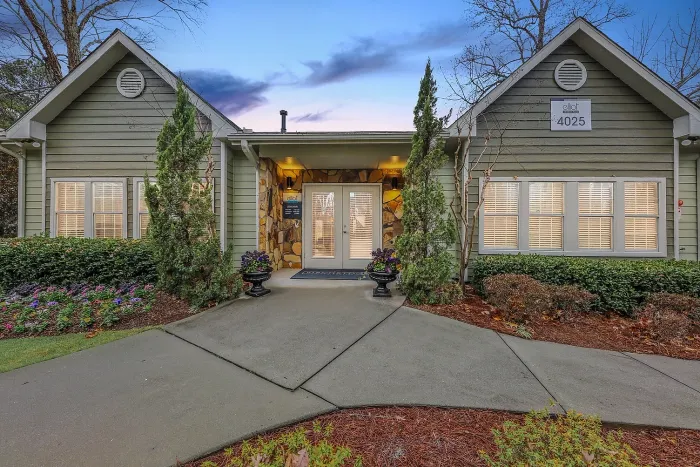 Charming leasing office exterior with elegant landscaping, inviting pathway, and serene twilight sky backdrop.