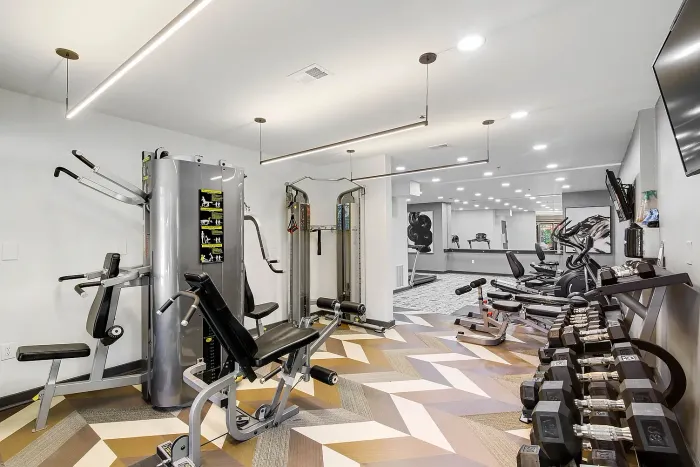 Modern fitness center featuring state-of-the-art gym equipment, sleek flooring, and a well-lit, spacious workout area.
