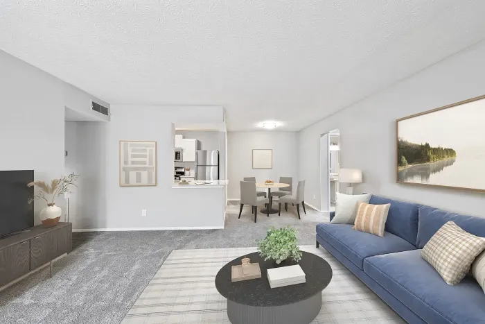Spacious apartment living and dining area with plush carpeting, modern furnishings, breakfast bar, and open kitchen with stainless steel appliances.
