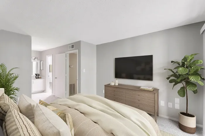 Spacious apartment bedroom with plush carpeting, wall-mounted TV, modern furnishings, and ensuite bathroom access.
