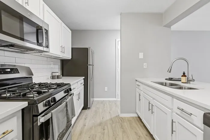 “Updated apartment kitchen with stainless steel appliances, quartz countertops, white shaker cabinets, subway tile backsplash, and modern fixtures.