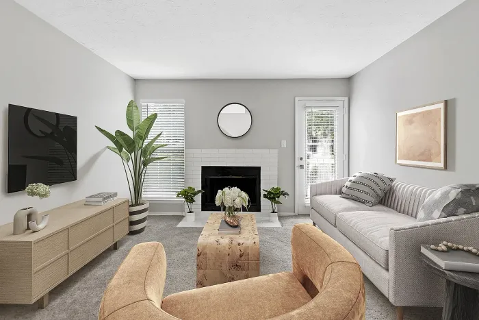 Stylish apartment living room with modern furnishings, decorative fireplace, wall-mounted TV, large windows, and access to private patio or balcony.