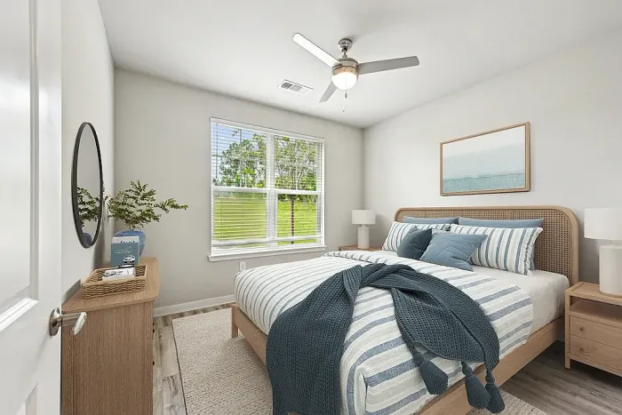Bright and cozy bedroom featuring a stylish modern bed with striped bedding, serene wall art, and a view of lush greenery through the window.