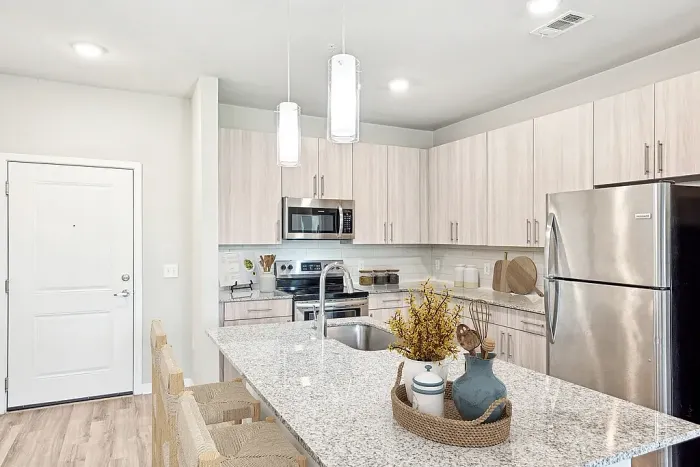 Modern kitchen with elegant granite countertop, stainless steel appliances, and ambient pendant lighting, creating a chic and inviting culinary space.