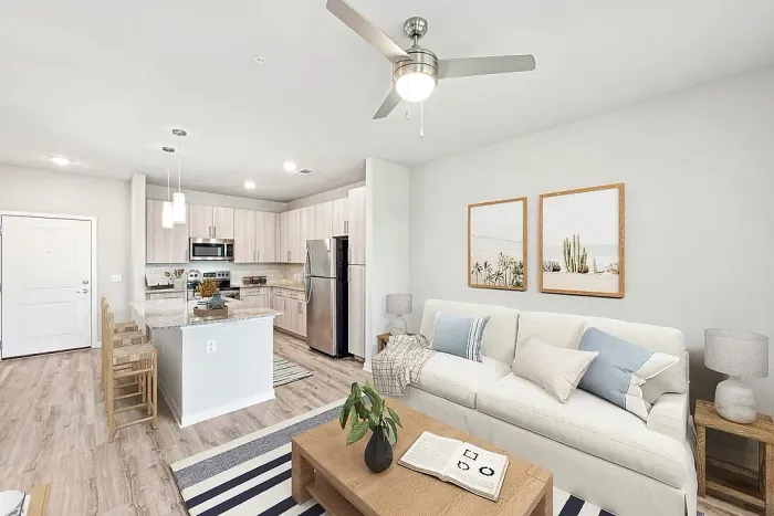 Modern open-concept living room featuring a cozy sofa, stylish kitchen with an island, and elegant decor.