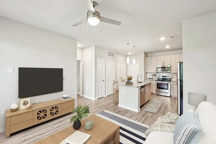 Bright, contemporary apartment living room with elegant hardwood flooring, modern kitchen island, and stylish ceiling fan.