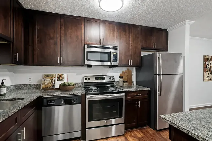 Modern kitchen with sleek dark wood cabinets, stainless steel appliances, and granite countertops.