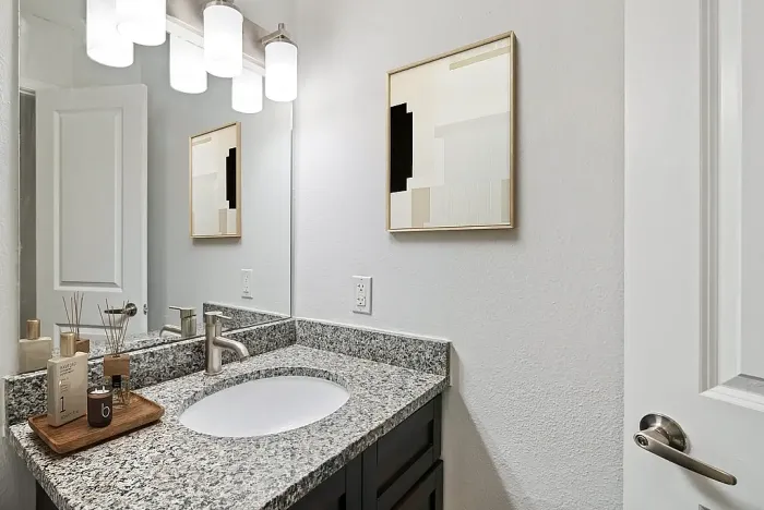 Modern bathroom with granite countertop, sleek faucet, and ambient lighting, accented by minimalist wall art.