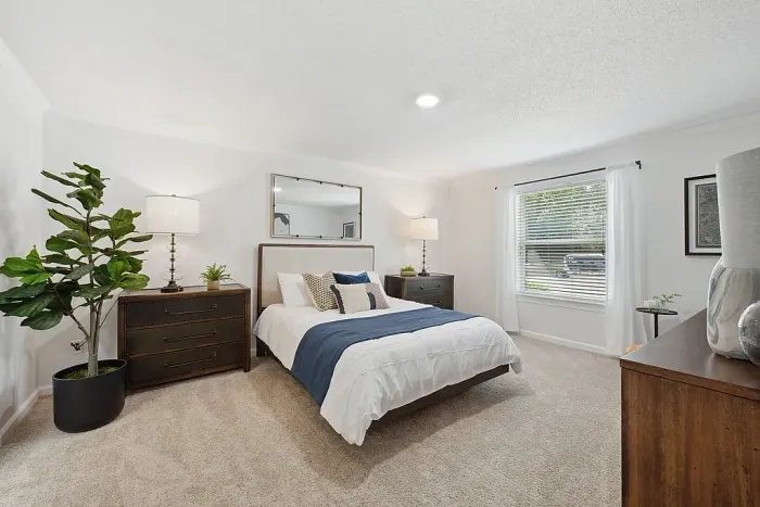Bright and airy bedroom with a modern design, featuring a cozy bed, stylish decor, and a large window with a scenic view.
