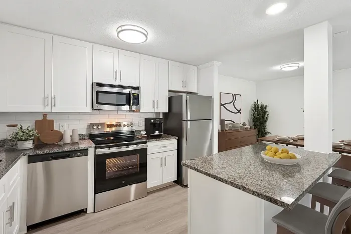 Modern kitchen with sleek stainless steel appliances, granite countertops, and elegant white cabinetry adjacent to a stylish dining area.
