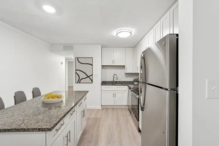 Modern kitchen with granite countertops, sleek stainless-steel appliances, and elegant white cabinetry, perfect for culinary enthusiasts.