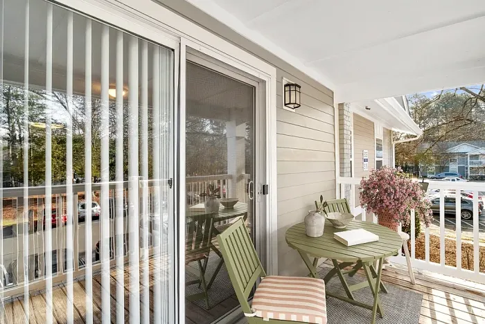 Charming apartment balcony with cozy seating, inviting ambiance, and vibrant pink flowers, perfect for relaxation.