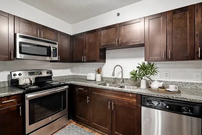 Modern kitchen with rich wood cabinetry, granite countertops, and stainless steel appliances for a luxurious culinary experience.
