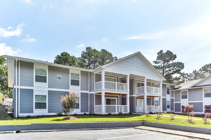 Charming modern apartment complex with elegant white-trimmed balconies and a serene natural setting.