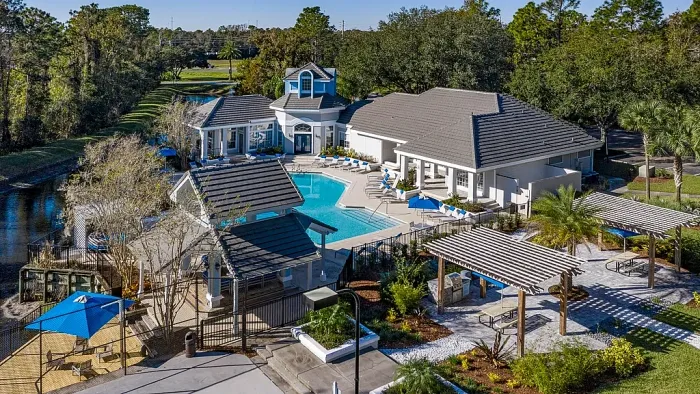 Aerial view of resort-style swimming pool with sundeck, clubhouse, cabanas, and outdoor grilling area.
