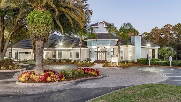 Leasing office exterior with palm trees, landscaped entrance, and circular driveway.
