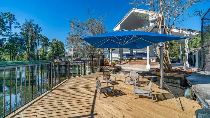 Wooden deck with lounge seating, large umbrella, and scenic waterfront views near clubhouse.