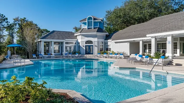 Resort-style pool with sun loungers, blue accents, and clubhouse.