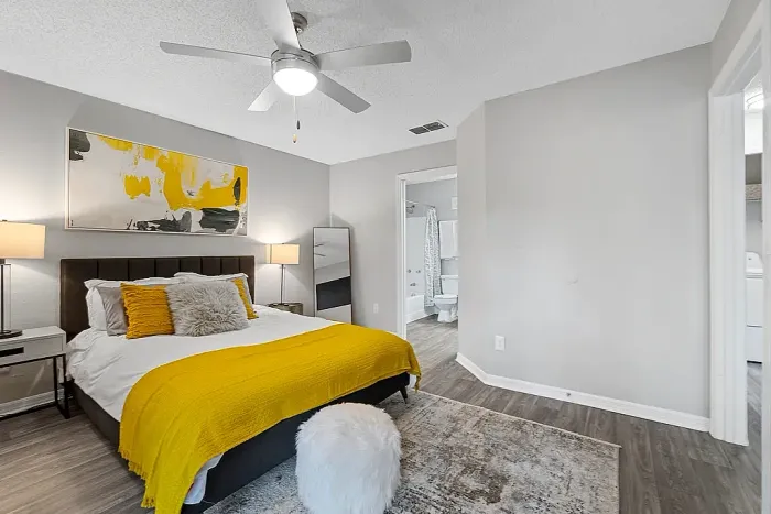 Spacious bedroom with ceiling fan, ensuite bathroom, and hardwood-style flooring.