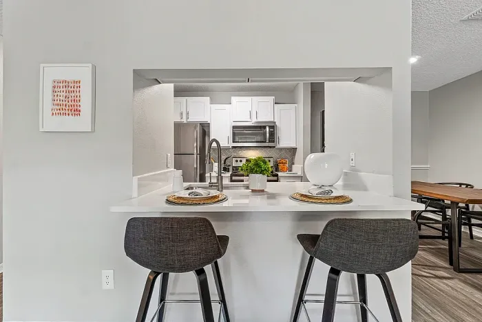 Modern kitchen with breakfast bar seating, white cabinets, and stainless steel appliances.