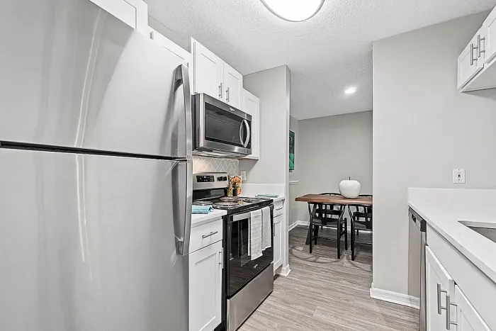 Modern kitchen with stainless steel appliances, white cabinets, and dining area.