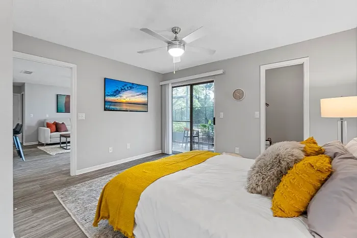 Spacious bedroom with ceiling fan, sliding glass door to patio, and hardwood-style flooring.