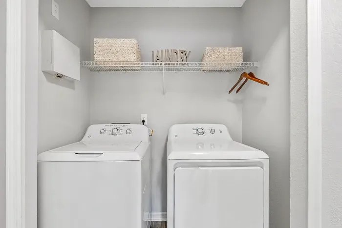 In-unit laundry with washer and dryer and overhead storage shelf.