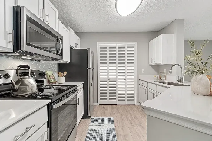 Modern kitchen with stainless steel appliances, white cabinetry, and whita quartz countertops.