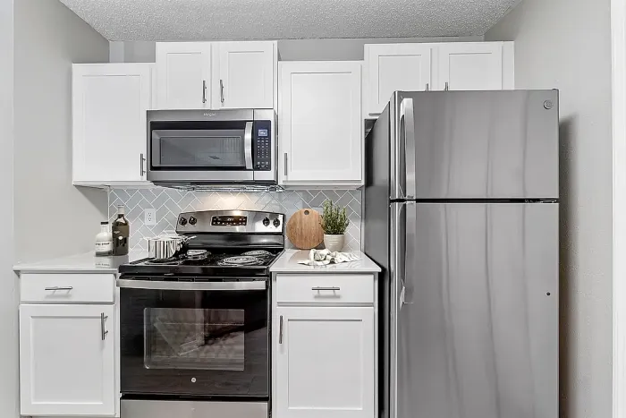Modern kitchen with stainless steel appliances, white cabinetry, and tile backsplash.