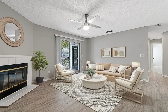 Bright living room with fireplace, ceiling fan, sliding glass door, and wood-style flooring.