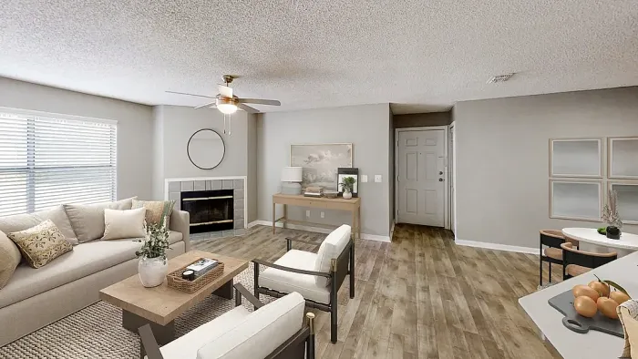 Bright open-concept living room with wood-style flooring, ceiling fan, and fireplace, featuring a cozy seating area and adjacent dining space.