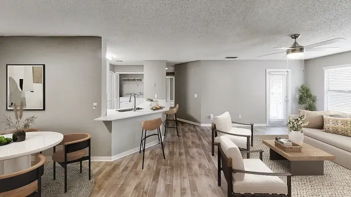 Open-concept living and dining area with wood-style flooring, breakfast bar seating, and a modern kitchen, featuring a bright living space with neutral finishes and ceiling fan.