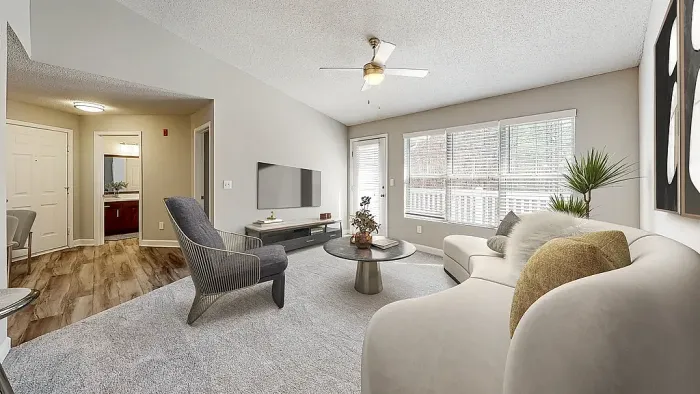 Modern apartment living room with plush carpeting, contemporary furnishings, large windows for natural light, neutral tones, and access to a private balcony or patio.