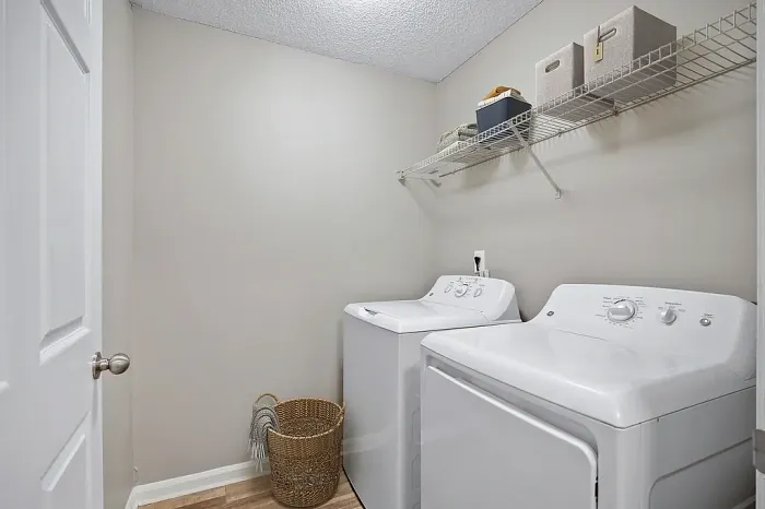 Dedicated laundry room with full-size washer and dryer connections, overhead storage shelving, and convenient space for everyday organization.