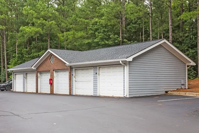 Detached garage buildings with convenient resident parking, classic brick-and-siding architecture, and a peaceful wooded community setting.