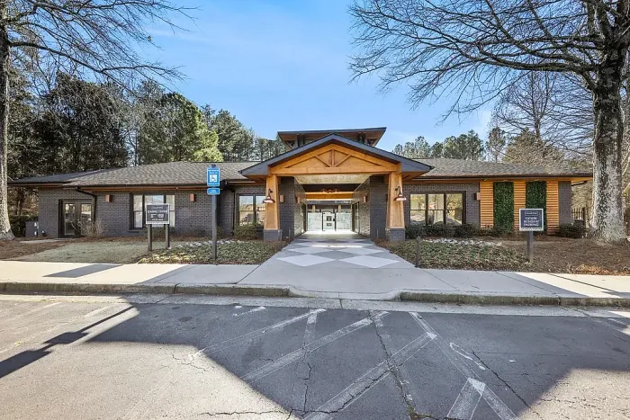 Modern leasing office exterior featuring stylish wood accents, welcoming architecture, landscaped surroundings, and a convenient central resident hub.