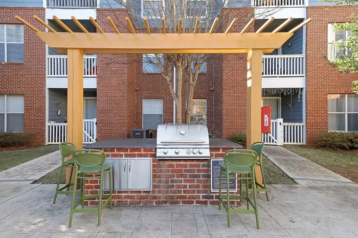 Outdoor grilling station with bar seating, stainless steel barbecue grill, and pergola-covered gathering space perfect for entertaining and outdoor dining.