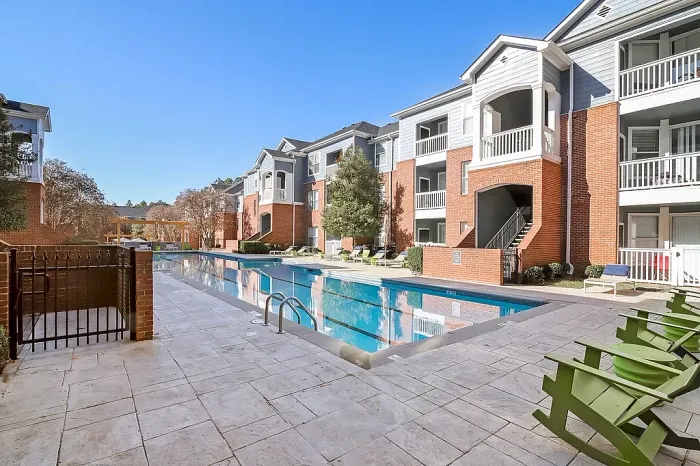 Resort-style swimming pool with spacious sundeck seating, modern apartment surroundings, and inviting outdoor spaces designed for relaxation and recreation.