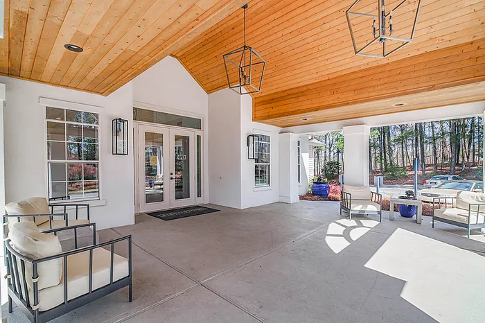 Inviting leasing office entrance with stylish seating under a warm wooden ceiling, offering a welcoming atmosphere in a tranquil setting.