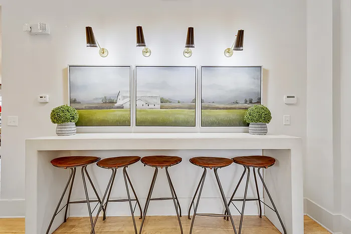 Chic breakfast bar with four modern stools, complemented by elegant lighting and serene landscape artwork, creating a stylish and inviting ambiance.