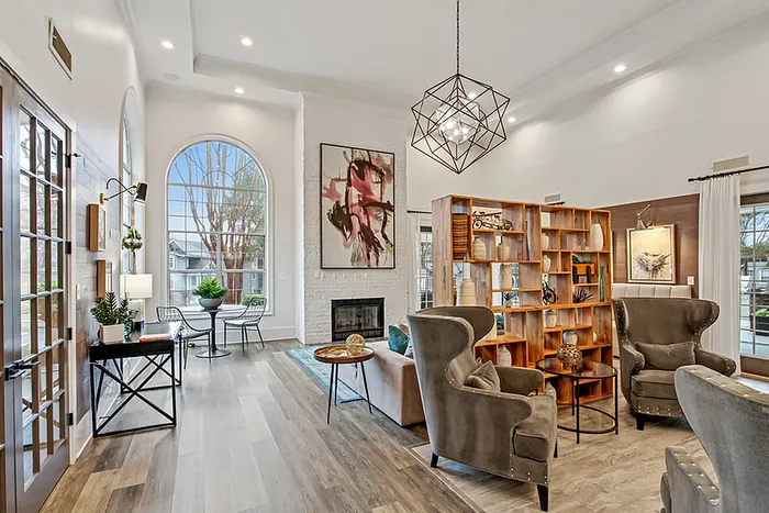 Elegant clubhouse with high ceilings, modern geometric chandelier, and large arched windows providing natural light. Open layout with sophisticated seating area, stylish decor, and a cozy fireplace.