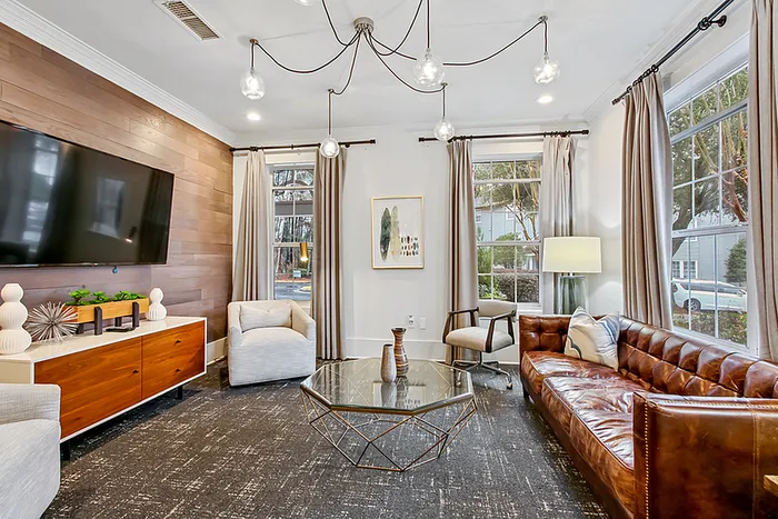Chic clubhouse with elegant decor featuring a large leather sofa, stylish armchairs, sleek wooden sideboard, and contemporary lighting.