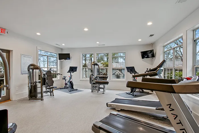 Bright and modern fitness center equipped with treadmills, stationary bikes, and strength training machines, featuring large windows and natural light.