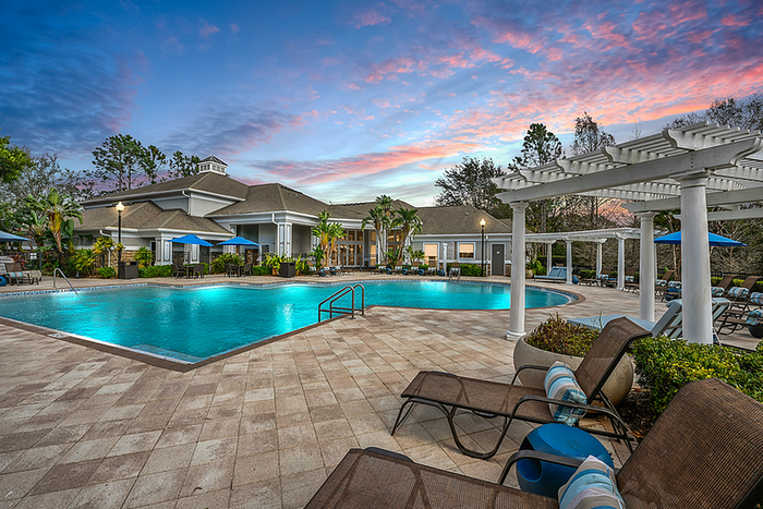 Luxurious poolside view at sunset featuring a refreshing swimming area surrounded by elegant lounge chairs and lush greenery.