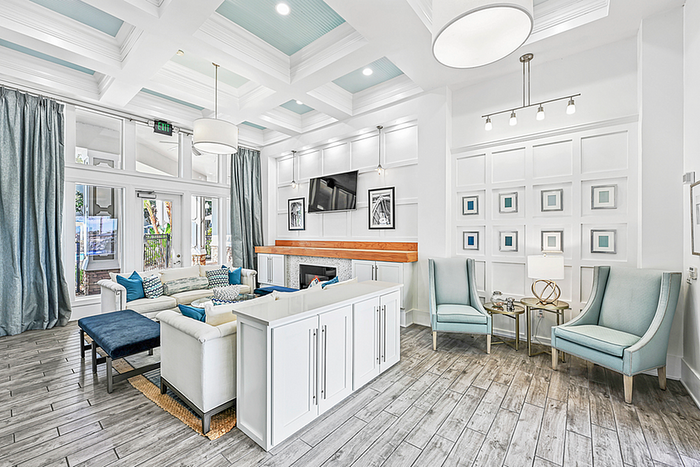 Elegant and inviting clubhouse with stylish white sofas, chic blue accents, and large windows providing abundant natural light. Perfect blend of modern design and cozy comfort.